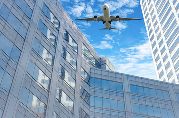 Wall Mural - Airplane flying in the sky above modern sustainable glass office building. Exterior skyscraper green glass building. Business travel. Aviation business. Air logistics. Cargo plane. Departure flight.