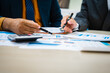 © NanSan - close-up of two professionals' hands meeting at a desk, discussing business strategies over a digital tablet and laptop. teamwork, planning, and communication in a corporate office setting.