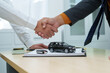 © NanSan - close-up of a car salesman handing the keys to an Asian customer after signing an insurance agreement. business transaction, ownership and customer service in the automotive industry.
