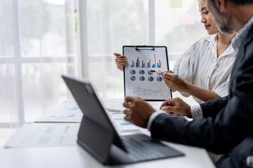 A man and a woman are looking at a presentation on a laptop