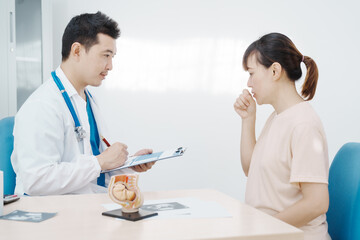 Asian female doctor listens to belly of pregnant mother during a prenatal exam in clinic. doctor provides caring advice, ensuring the health and happiness of the expecting mother and baby.