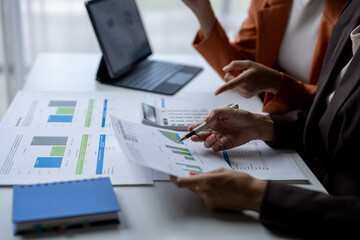 Wall Mural - Two businesswomen analyzing financial charts and data on desk