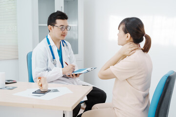 asian female doctor listens to belly of pregnant mother during a prenatal exam in clinic. doctor pro