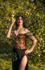 Black hair woman in dark clothes on a nature background, corset with ethnic prints, Slavic style 