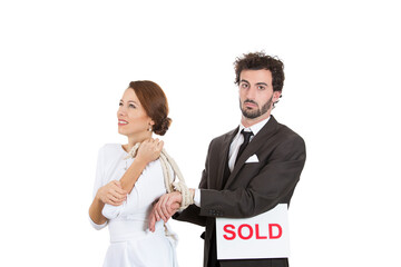 portrait of a young couple, businesspeople, female woman happy have male man hands tied up with rope, guy holding sold sign