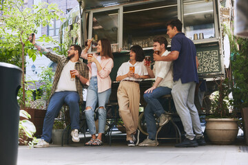 Wall Mural - Happy smiling people, friends, men and women meeting at local outdoor bar, drinking beer and taking selfie with mobile phone. Cozy memories. Concept of relaxation, party, beer, festival, celebration