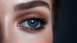 © Prostock-studio - A womans eye showcases a vivid blue iris, accented by shimmering eyeshadow and long eyelashes against a dark background.