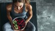© The Little Hut - Top view of a happy sporty slim woman in sportswear eating healthy food after working out sitting on yoga mat Fit girl with a bowl of fruits and berries Healthy nutrition and lifestyle : Generative AI