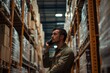 © Mikki Orso - Man working in warehouse while manager talks on phone   industrial setting photography