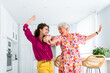 © oneinchpunch - Beautiful grandmother and granddaughter together at home dancing and having fun - Cheerful granma and nephew spending quality time together