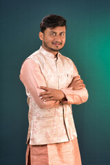 Portrait of a happy young man posing with arms crossed or hands folded on a dark background