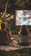 © liliyabatyrova - A group of people sits on a blanket in a backyard, focused on a movie projected on a screen, surrounded by string lights and greenery, creating a relaxed evening atmosphere