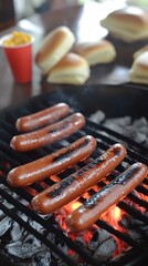 Wall Mural - Hot dogs grilling over hot coals on a barbecue grill.