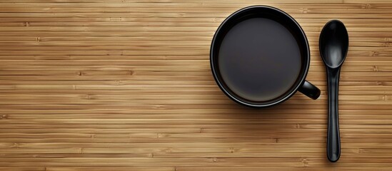 Poster - Black coffee cup with spoon on a bamboo surface Copy space Top view Flat lay Top down