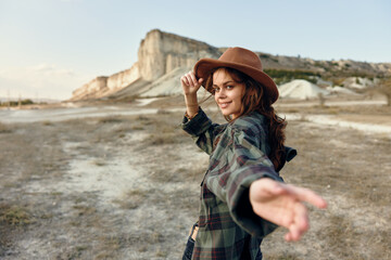 Wall Mural - Woman in plaid shirt and hat standing in front of majestic mountain landscape