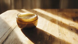 Creme jar with its rich contents being smoothly applied on a polished wooden surface, bathed in soft, natural light for a luxurious and refined feel