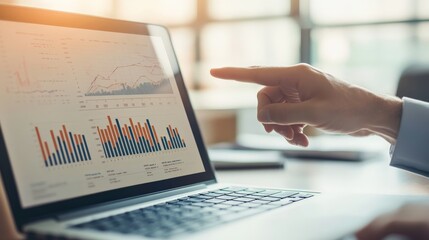 Leinwandbilder - A hand pointing at an analytical graph displayed on a laptop screen in a sunlit office setting, demonstrating the business analysis and strategy review process.