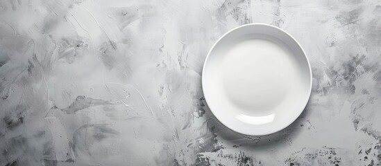 An empty white plate on a white stone table top view copy space