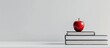 © Ilgun - Back to school a stack of books and a red apple on a white table against a white background Remote learning at home Quarantine idea of staying home. Copy space image. Place for adding text and design