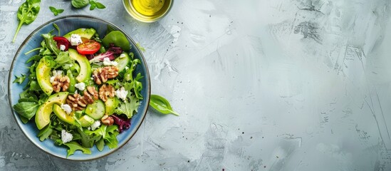 Colorful lunch spring salad Fresh greens avocado walnuts feta cheese and olive oil in a blue bowl The meal is photographed from above top view flat lay on a pastel stone surface Free copyspace