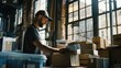 © VK Studio - A focused warehouse worker categorizes packages in a bright workspace, surrounded by large windows and a variety of shipping boxes.