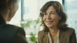 © VK Studio - A smiling woman engages in a lively conversation, exuding warmth and approachability in a professional setting.
