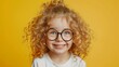 © VK Studio - A curly-haired child wearing glasses smiles widely against a yellow background, radiating pure joy and energy.