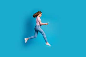 Poster - Full body photo of attractive young woman running hold device dressed stylish striped pink clothes isolated on blue color background