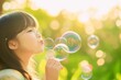 © Kamarizal Kamarludin - A young girl blowing soap bubbles outdoors on a sunny day, with soft light and greenery in the background. A scene full of innocence and joy.