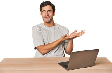 Hispanic young man working on laptop holding a copy space on a palm.