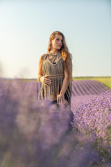 Wall Mural - A woman is standing in a field of purple flowers, wearing a black dress and a black hat.