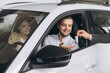 © anatoliycherkas - Happy couple buying car in huge showroom, taking automobile key from young handsome salesman while sitting inside auto. Cheerful arab man and woman purchasing beautiful vehicle, closeup