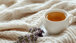 © Matthias - Cozy knitted blanket and cup of tea on clean background, ideal for relaxation or self-care content