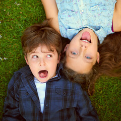 Canvas Print - Funny face of brother and sister with tongue out on grass from above in garden for bonding together. Face, happy and humor with sibling children on lawn in backyard for comedy or playful joking