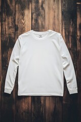 A mockup of a blank adult long sleeve t-shirt lying flat on a dark wooden floor. The t-shirt is neatly arranged, with a clean and professional appearance