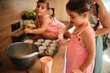 © chika_milan - In a kitchen, two young girls and a woman are preparing muffin batter. The girls are engaged in the activity, showcasing family bonding and joy in a cozy setting.