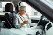 © Davor - Smiling senior businesswoman using smartphone in car