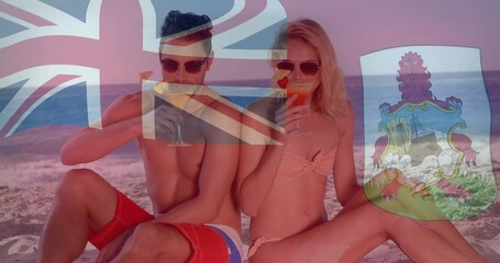 Wall Mural - Flags of Bermuda and United Kingdom animation over couple enjoying drinks on beach