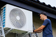 © Vasil - A man is working on an air conditioner. He is wearing a blue shirt and a hat