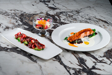 Canvas Print - Lunch salmon fillet with spinach and sauces and cold appetizer carpaccio with tuna, avocado, algae, strawberries, spinach, sesame seeds and dessert.