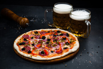 Wall Mural - Italian pizza with sausage, cheese, sweet pepper, olives, jalapeno pepper, red onion on thin dough with two glasses of beer.