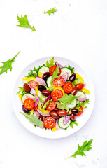 Wall Mural - Vegan vegetable salad with olives, tomato, paprika, cucumber and onion, healthy mediterranean food. White background, top view