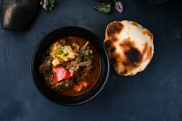 Canvas Print - Fresh stewed beef with potatoes, sweet peppers, onions in tomato sauce with herbs and flatbread in a bowl.