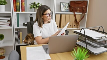 Sticker - A young hispanic woman works in an office alongside her dog, portraying a modern, pet-friendly workplace.