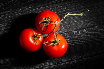 Wall Mural - tomato branch on black wood background top view