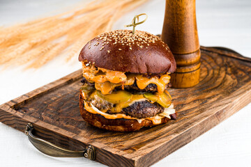 Wall Mural - American food beef burger with pickled cucumbers, cheddar cheese, lettuce and sauce on wooden board.