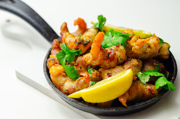 A black pan with shrimp and lemon slices