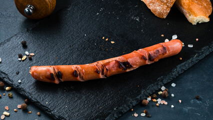 Wall Mural - English breakfast fried sausage with bread, salt and pepper on a dark background.