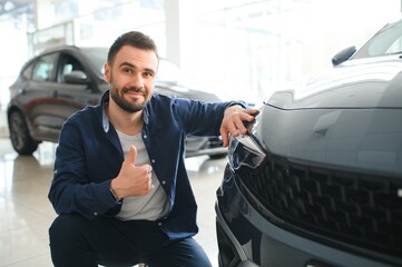 Wall Mural - Young man is choosing a new vehicle in car dealership