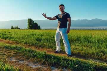 Wall Mural - Young strong successful man posing in summer field on mountains background